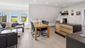 Eine moderne Küche mit Essbereich, ausgestattet mit einem Holztisch, Stühlen und einer Couch.