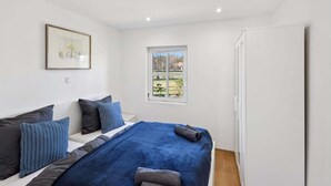 Una camera da letto con un letto, cuscini, una finestra e una porta.