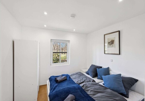 Un dormitorio con dos camas, una ventana con vistas y un cuadro en la pared.