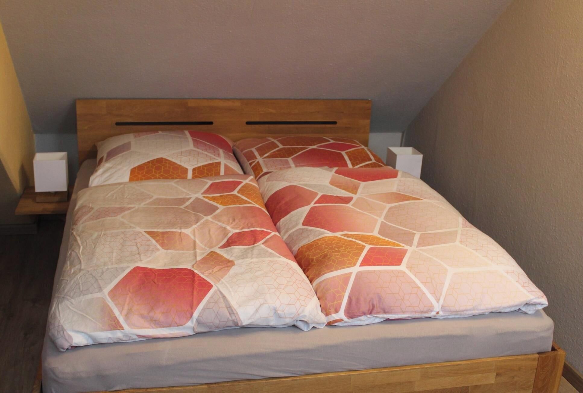 A bed with a wooden headboard, two bedside tables, and a patterned bedspread.