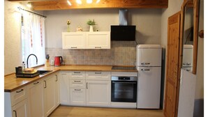 A kitchen with white cabinets, a wooden countertop, a built-in oven, and a refrigerator. - Ferienhaus in Rethwisch (Rethwisch)