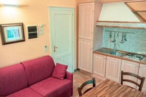 A compact living space with a kitchenette, a sofa, a dining table, and a door. - Holiday Home near Mount Subasio (Assisi)