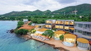Un hôtel situé sur la côte, avec plusieurs étages, des espaces de détente en plein air et une piscine.