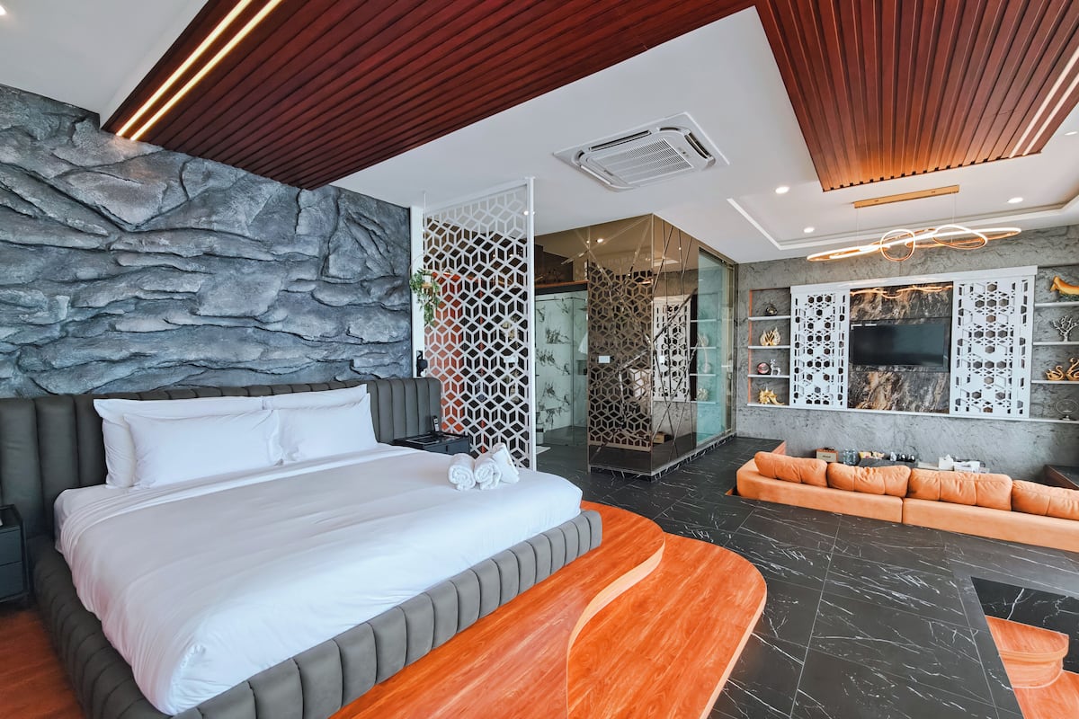 Une chambre d’hôtel moderne dotée d’un grand lit, d’un coin salon et d’un mur décoratif en pierre.