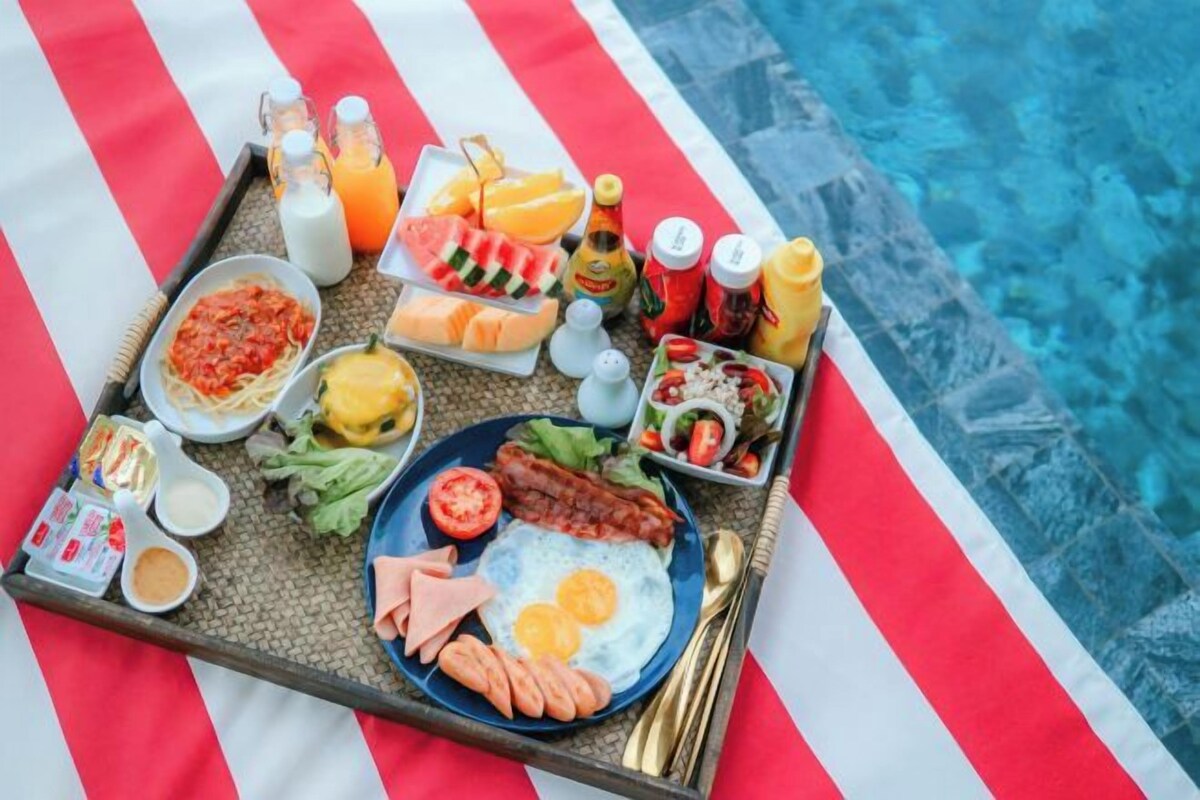 A breakfast tray with various foods and drinks by a poolside.