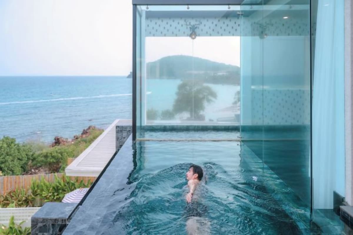 A glass-enclosed infinity pool with a view of the sea and a distant island.