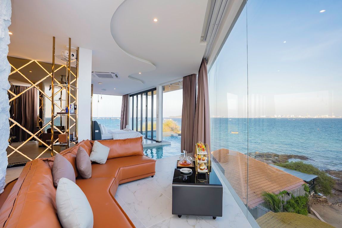 A modern living room with a large window overlooking a body of water, a plush orange sofa, and a small table with a tray of items.