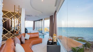 A modern living room with a large window overlooking a body of water, a plush orange sofa, and a small table with a tray of items.