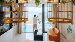 Un intérieur moderne avec une porte vitrée donnant sur un balcon, un canapé et un téléviseur sur le mur de gauche.