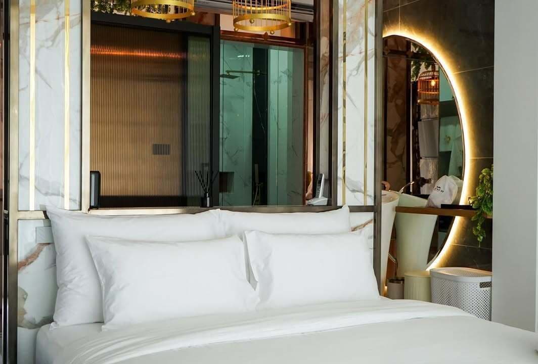 A modern bedroom with a large bed, a glass partition, and a curved mirror.