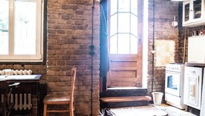 A rustic kitchen with a brick wall, wooden door, and white cabinets. - Poetic Studio with Garden (Berlin)