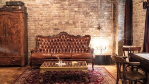 A vintage-style room with a leather sofa, a wooden cabinet, and a dining table with chairs. - Poetic Studio with Garden (Berlin)