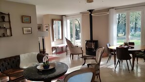 Ein großzügiges Wohnzimmer mit Kamin, bequemen Sitzmöglichkeiten und großen Fenstern mit Blick ins Freie.