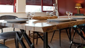 A dining area with a wooden ceiling, a table set with plates, glasses, and a pitcher, and a chair with a black cushion. - Gîte chez Alice et Marcel: sauna, cabin, chicken coop, bicycles & garden. (Saulxures-sur-Moselotte)