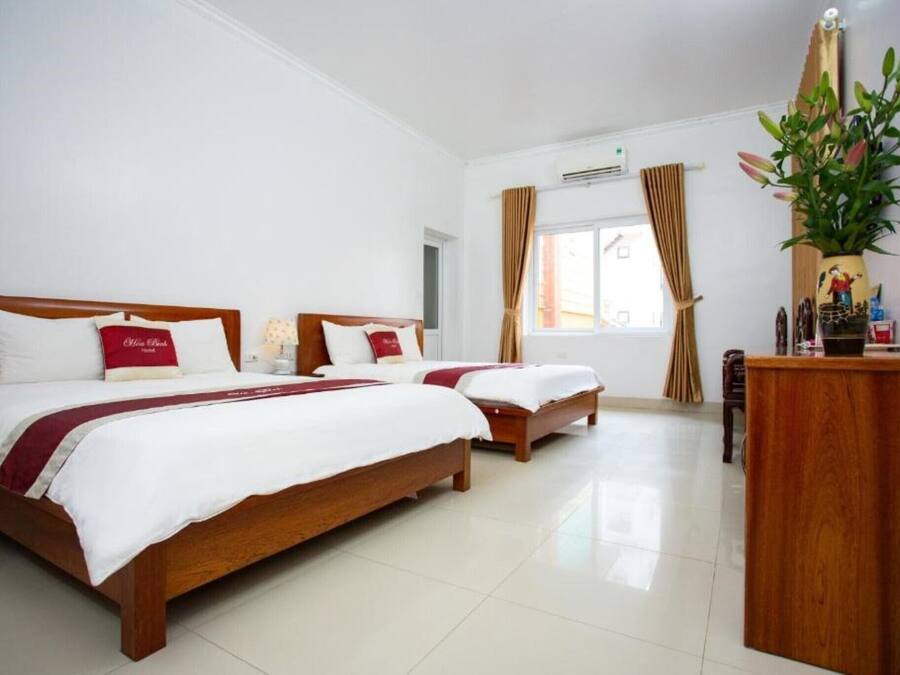 A hotel room with two wooden beds, a wooden desk, and a large window with curtains.