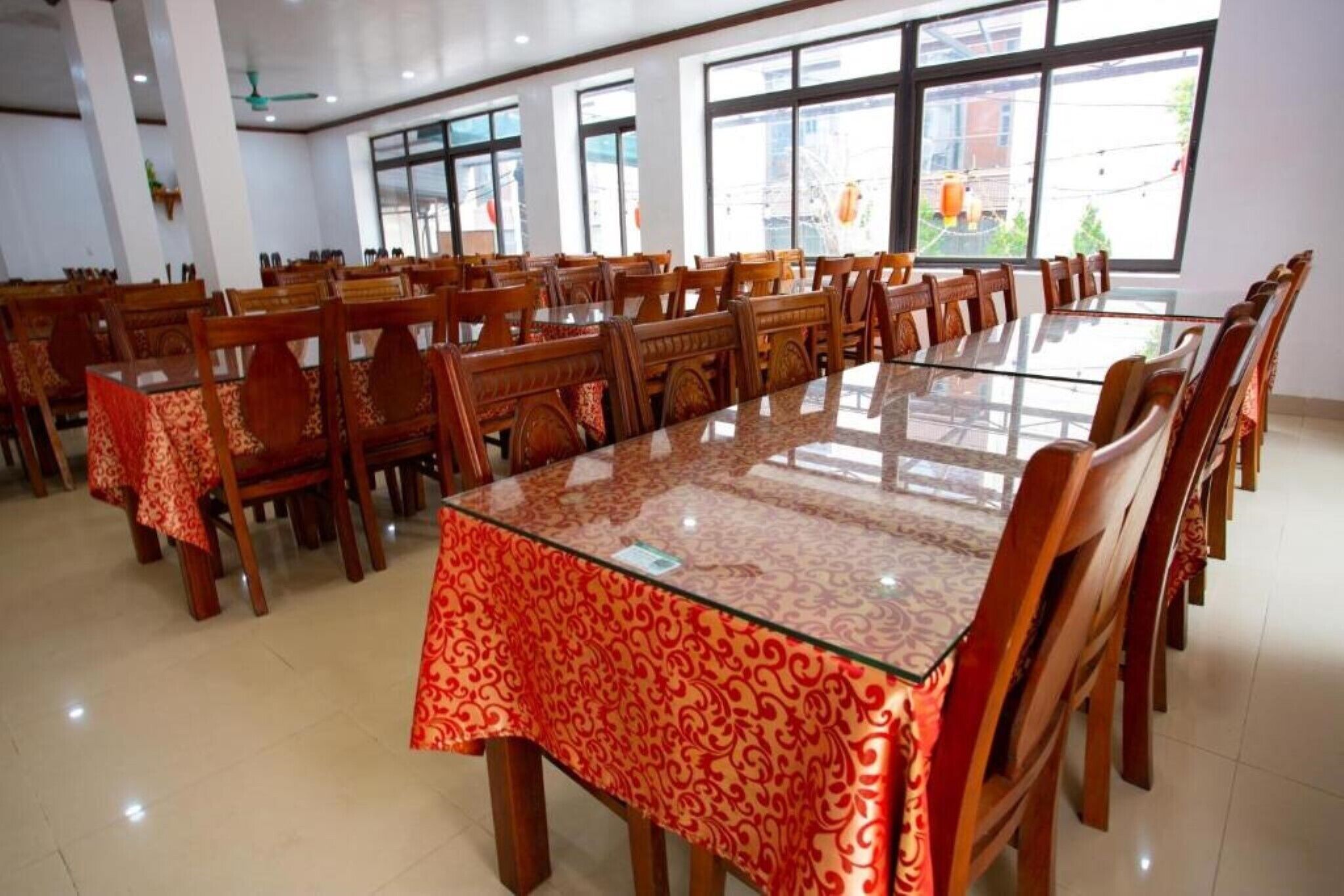 A large conference room with a glass table and wooden chairs, large windows, and a tiled floor.