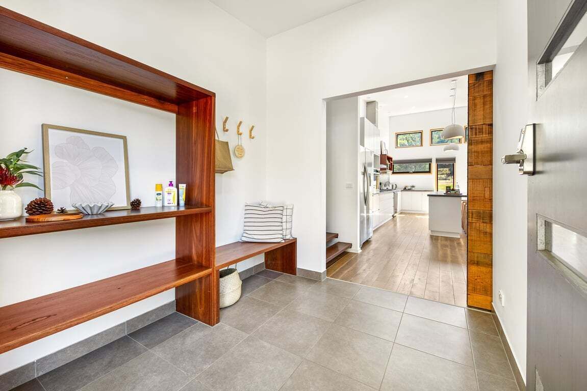 A modern kitchen with a wooden bench, a framed picture, and a hanging bag.