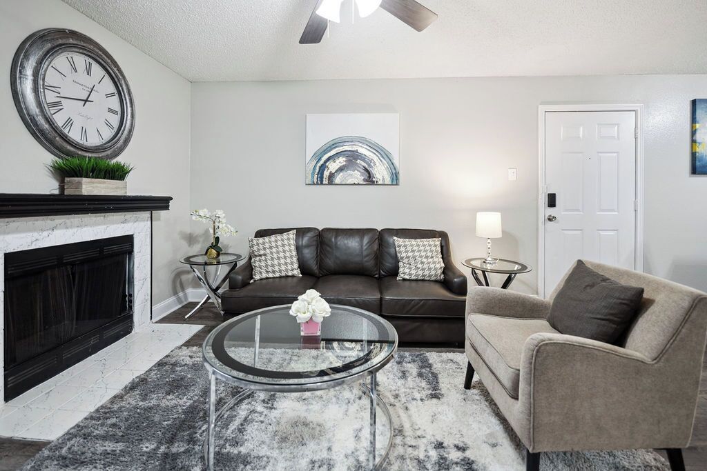 A living room with a fireplace, a round glass coffee table, a sofa, and a door.