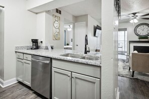 A modern kitchen with white cabinetry, granite countertops, and stainless steel appliances. - I015 – Upgraded 2BD | Pool | DFW South 183/161 (Irving)