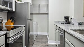 Een moderne keuken met roestvrijstalen apparatuur, een granieten aanrechtblad en een houten vloer.