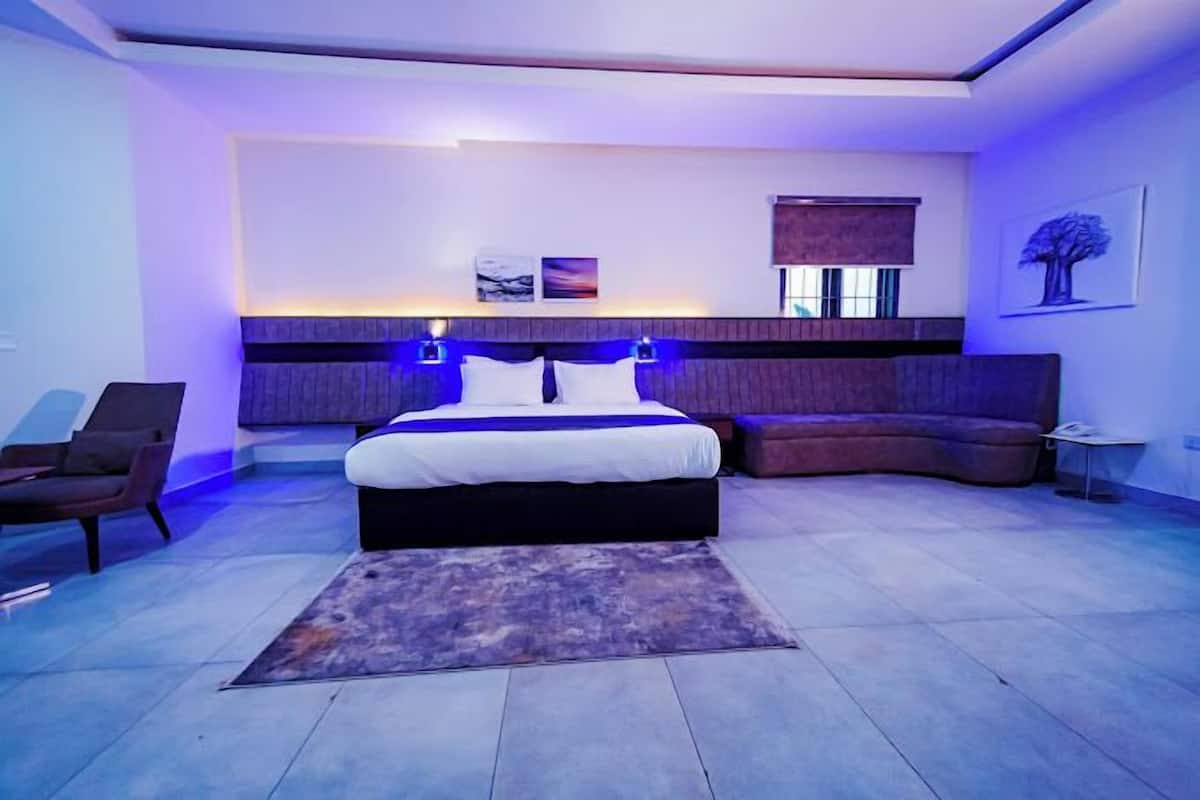 A modern bedroom with a large bed, a curved sofa, and a small side table.
