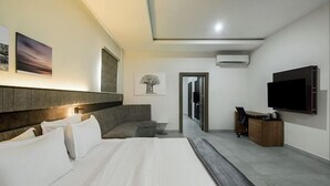 A modern hotel room with a large bed, a desk, a television, and artwork on the walls. - D'Stolz Villa and Hospitality (Abuja)