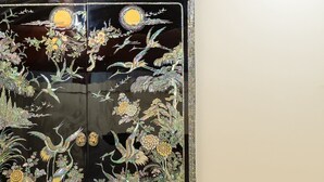 En grøn sofa med en pude med tekst, en dekorativ panel med blomstermotiver, og en lille kage på sofaen.