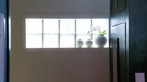 Et vindue med tre hvide vaser med blomster, en dør med greb og en lyskontakt på væggen.