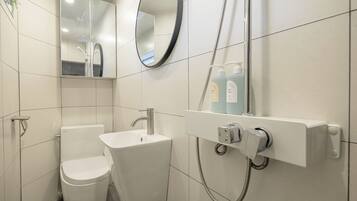 A modern bathroom with a toilet, sink, and shower unit.