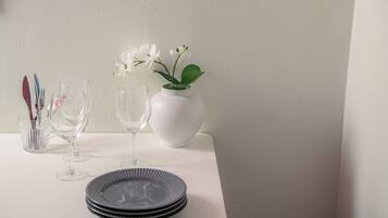 Et bord med en vase med hvide blomster, vinglas og stablede tallerkener.