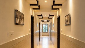 Passadís d'hotel modern amb un recorregut directe, obra d'art als murs i una finestra gran al final.