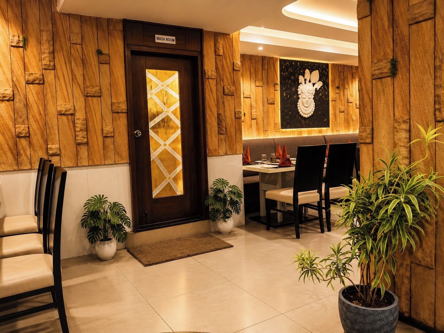 A hotel lobby with a wooden wall, a reception desk, seating area, and a washroom sign.