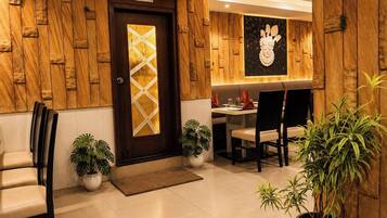 A hotel lobby with a wooden wall, a reception desk, seating area, and a washroom sign.