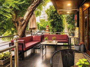 An outdoor seating area with a red sofa, a table, and potted plants. - HOTEL THE ARCHI (Udaipur)