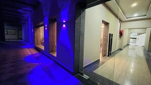 A hallway with a checkered floor, a glass door, and a red fire alarm. - HOTEL THE GRAND AGASTYA (Singrauli)
