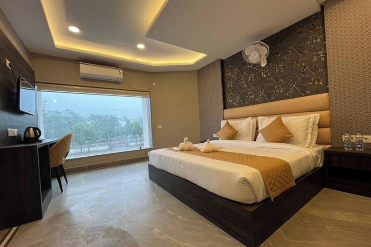 Habitación de hotel moderna con una cama grande, un escritorio y vistas al exterior.