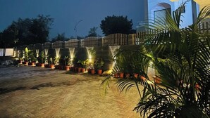 An outdoor area with a paved surface, potted plants, and a fence. - HOTEL THE GRAND AGASTYA (Singrauli)