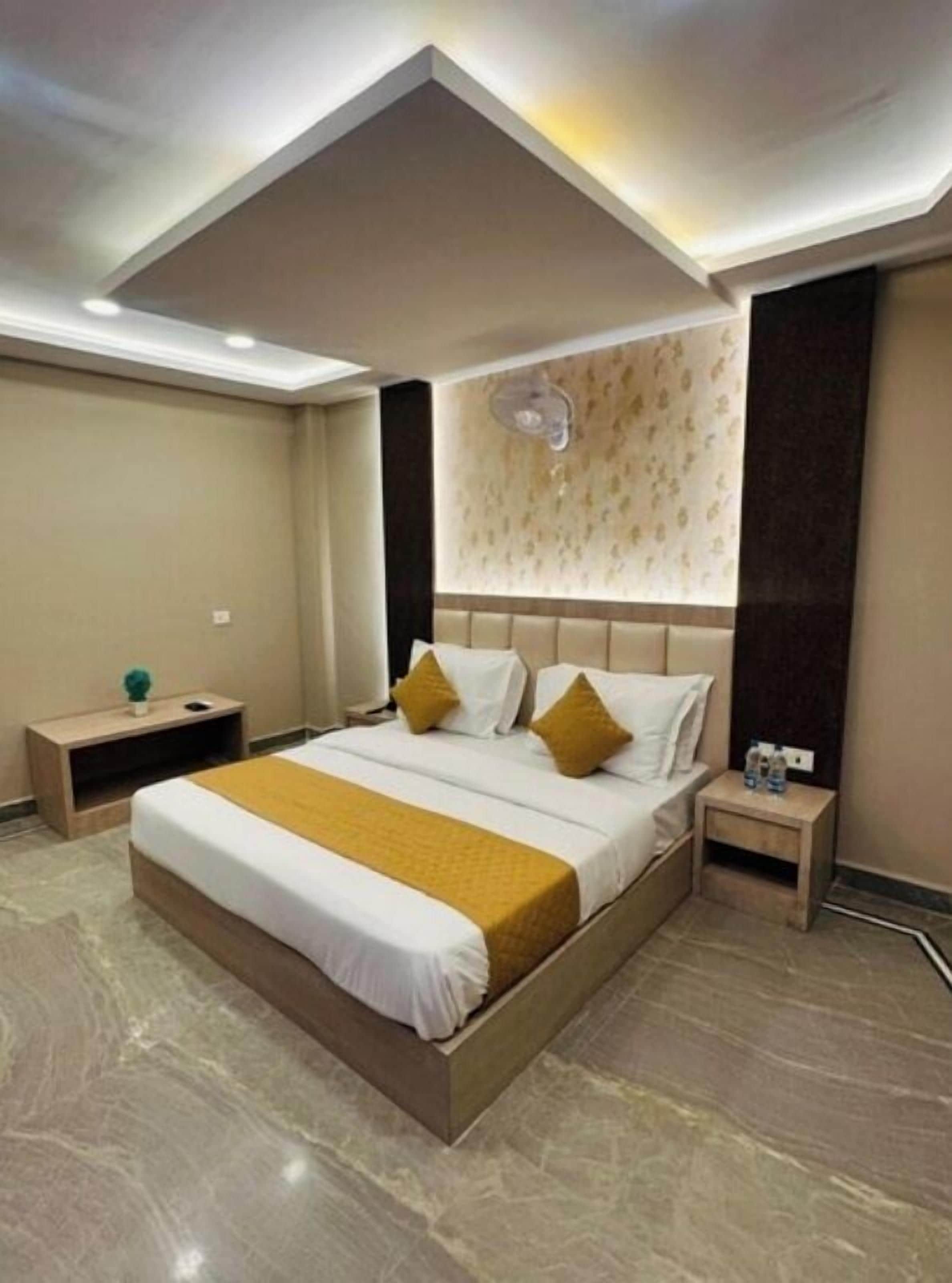 Una habitación de hotel moderna con una cama grande, una mesita de noche y una lámpara en el techo.