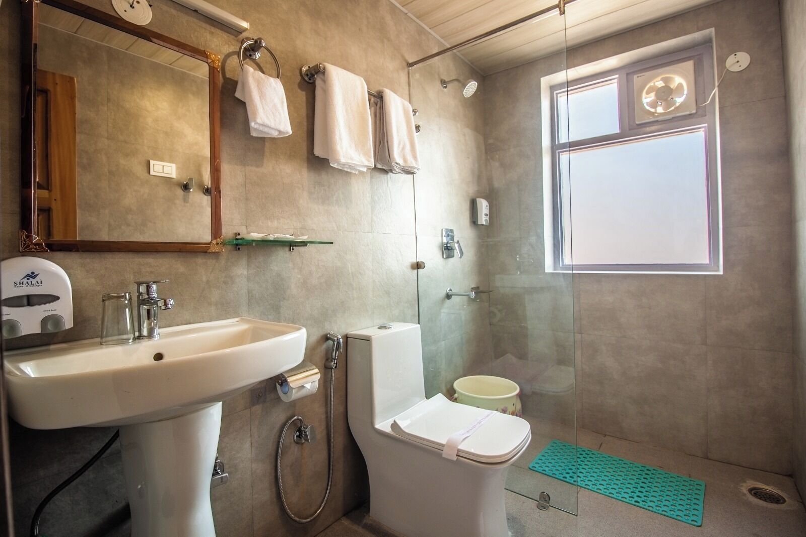 A bathroom with a sink, toilet, and shower. There is a towel rack with towels, a mirror, and a window.