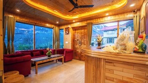 Una habitación acogedora con techo de madera, un sofá rojo, una mesa de centro de madera y vistas a montañas a través de grandes ventanales.