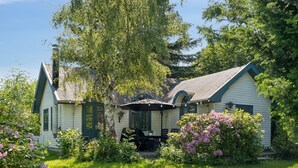 Ein Haus mit einem grünen Dach, weißen Wänden und einer Veranda mit einer überdachten Sitzgruppe.