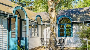 Ein Haus mit Veranda, einem Baum und Topfpflanzen.