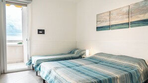 Ein Zimmer mit zwei Betten, einer Balkontür und einer Wand mit drei Bildern.