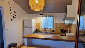 Cocina compacta con encimera de madera, un refrigerador, un fregadero y una zona de comedor con mesa y sillas.