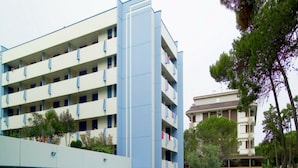 Un hotel con varias plantas, piscina y jardín.