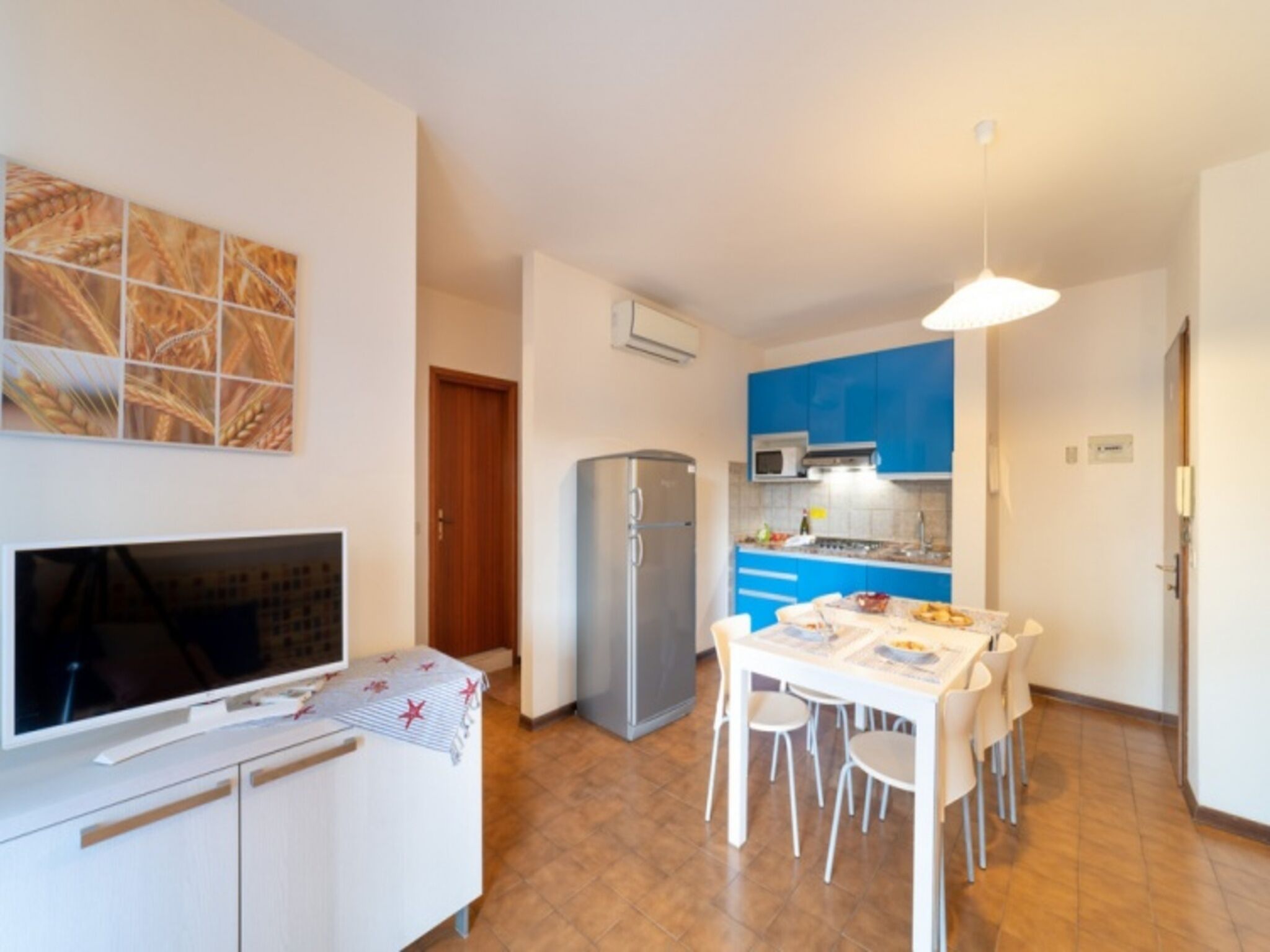 A compact kitchen with a refrigerator, microwave, and a dining area with a table and chairs.