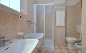 A bathroom with a bathtub, a shower, a toilet, and a sink. - Spacious apartment 50mt from the beach (Bibione)