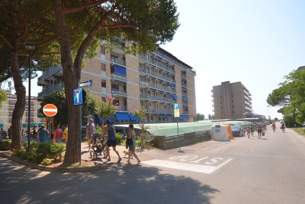 Un hotel de varios pisos con balcones, un estacionamiento y un paso de peatones.