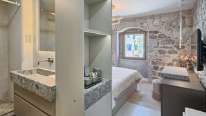 A modern bathroom with a large marble sink, a built-in mirror, and a shower area.