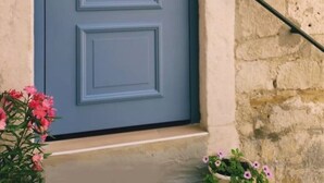 A light blue door with a black handle and a small keyhole, set in a stone wall.